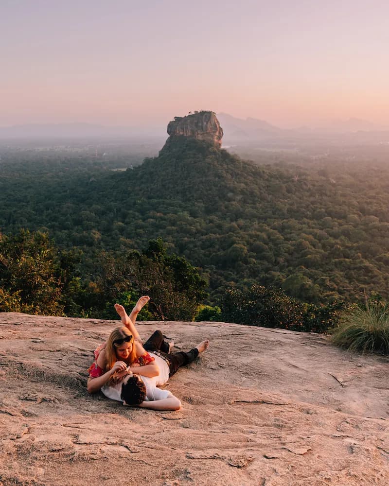 Couple resting on a rock with Sigiriya in the distance